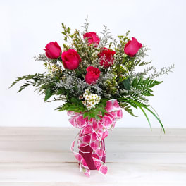Pink roses in a vase with a decorative ribbon