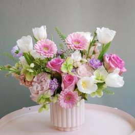 Pink and white mixed flower arrangement in a ribbed vase