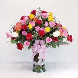 Mixed roses in a glass vase with a pink plaid ribbon