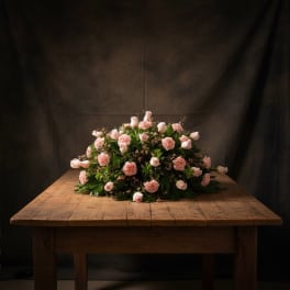 Low arrangement of pale pink flowers on a wooden table