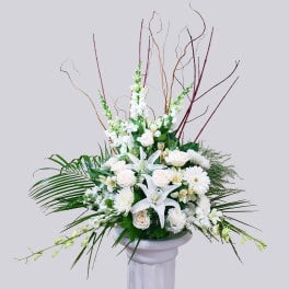 White floral arrangement in a pedestal vase with tall branches