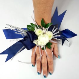 White floral wrist corsage with blue ribbon accents