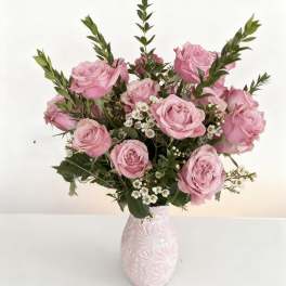 Pink roses arranged in a patterned vase with small white filler flowers
