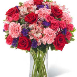 Bouquet of red roses and pink carnations in a clear glass vase