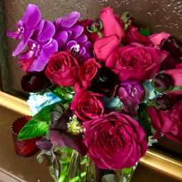 Bouquet of pink roses and purple orchids in a glass vase