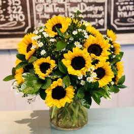 Bouquet of yellow sunflowers and small white daisies in a glass vase