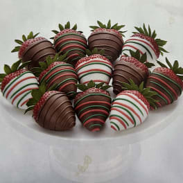 Plate of chocolate-covered strawberries with red, green, and white drizzle