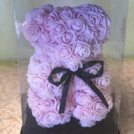 Pink rose-shaped arrangement in a clear display box with a black ribbon