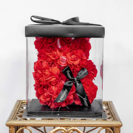 Red rose teddy bear in a clear gift box with a black ribbon