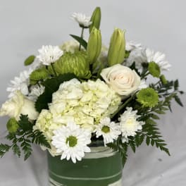White and green floral arrangement in a square glass vase
