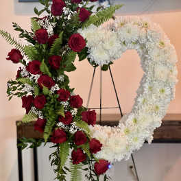 Heart-shaped floral wreath with red roses and white chrysanthemums on an easel