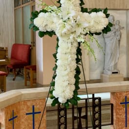 White floral cross on an easel in a church interior
