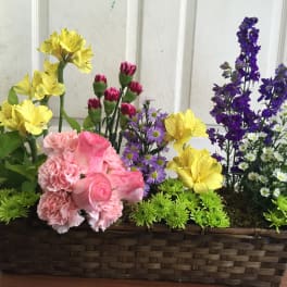 Mixed flowers in a rectangular wicker basket with pink, yellow, purple, and white blooms