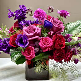 Bouquet of pink, red, and purple flowers in a dark glass vase