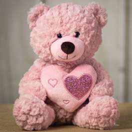 Pink teddy bear holding a glittery heart pillow