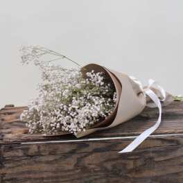 Bouquet of white baby's breath wrapped in brown paper with a white ribbon