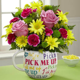 Pink roses and yellow daisies in a mug-shaped vase