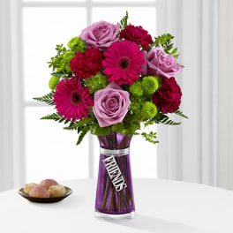 Pink and lavender flowers in a purple vase with a FRIENDS tag