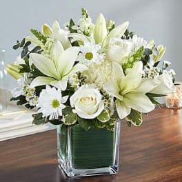 White lilies and roses arranged in a square glass vase