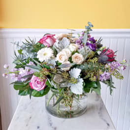 Mixed bouquet of pink, white, and lavender flowers in a glass vase