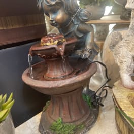 Decorative cherub fountain statue with water flowing into a basin