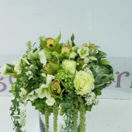 Green and white floral arrangement in a round container