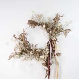 Dried floral wreath with ribbons on a white wall