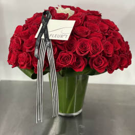Large bouquet of red roses in a glass vase with a black-and-white ribbon
