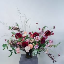 Large mixed bouquet of pink and burgundy flowers in a dark vase