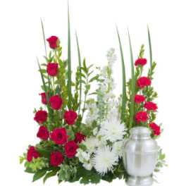 Red roses and white flowers arranged beside a silver urn