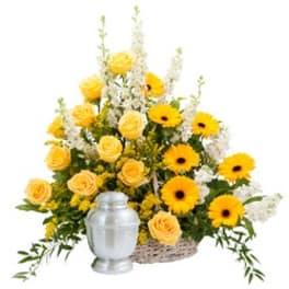 Yellow roses and gerbera daisies in a basket with a silver urn