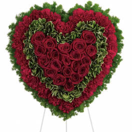 Heart-shaped floral tribute with red roses and carnations on a stand