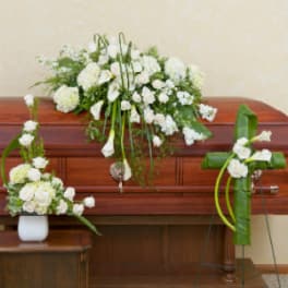 White floral arrangements displayed on a wooden casket