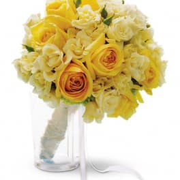 Yellow and white rose bouquet in a clear glass vase with ribbon