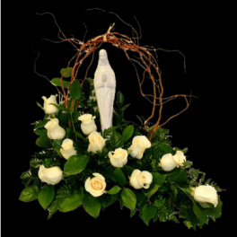 White roses arranged around a white statue under a twig arch