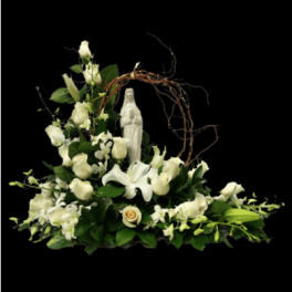 White floral arrangement with lilies and roses around a religious statue