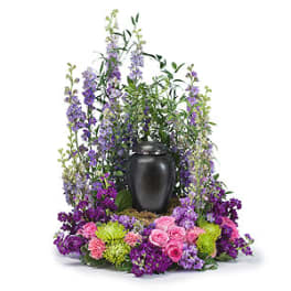 Purple and pink floral arrangement around a black urn
