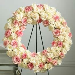 Circular wreath of pink and white roses on a black stand