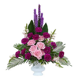 Pink roses and purple flowers arranged in a white vase