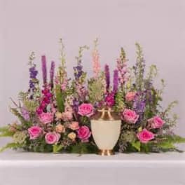 Pink roses and purple flowers arranged around a white urn