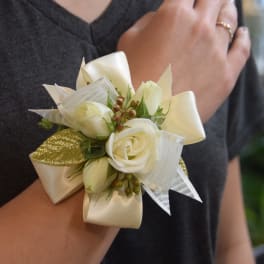 Ivory rose wrist corsage with satin and sheer ribbons on a person’s wrist