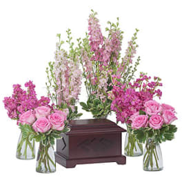Pink rose bouquets and tall pink floral sprays around a wooden urn