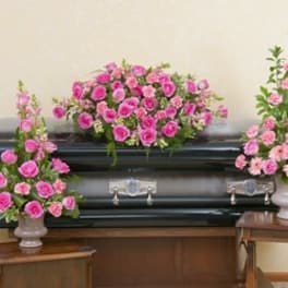 Pink floral arrangements displayed around a black casket