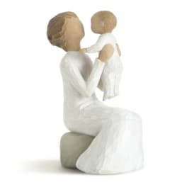 Two white figurines of a seated woman holding a child