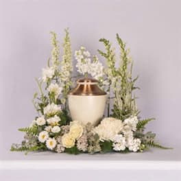 White floral funeral urn arrangement with tall blooms and a copper urn