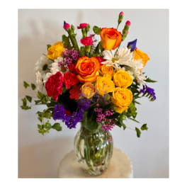 Colorful bouquet of roses, carnations, and daisies in a glass vase