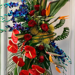 Tall tropical floral arrangement with red roses, blue orchids, and orange bird-of-paradise