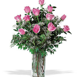 Pink roses arranged in a tall clear glass vase