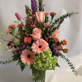 Mixed bouquet in a clear glass vase with pink roses, gerberas, and green hydrangea