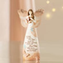 A blurred angel figurine in a white dress with wings and a small heart.